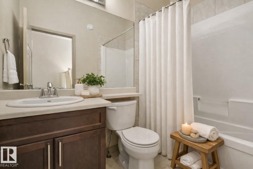 Bathroom featuring a modern vanity with wood-finish cabinetry, a single basin sink, and a large wall-mounted mirror - 21851 80 Avenue, Edmonton, AB - Indoor Photo Showing Bathroom