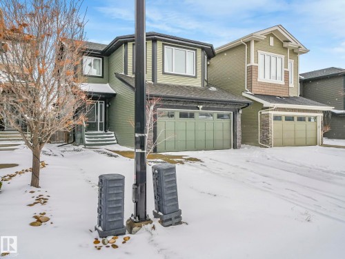 Green-sided residence featuring a prominent bay window, attached garage, and covered front entry - 21851 80 Avenue, Edmonton, AB - Outdoor With Facade