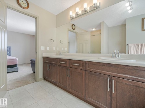 Dual sink vanity with dark wood-finish cabinetry and light countertops - 21851 80 Avenue, Edmonton, AB - Indoor Photo Showing Bathroom