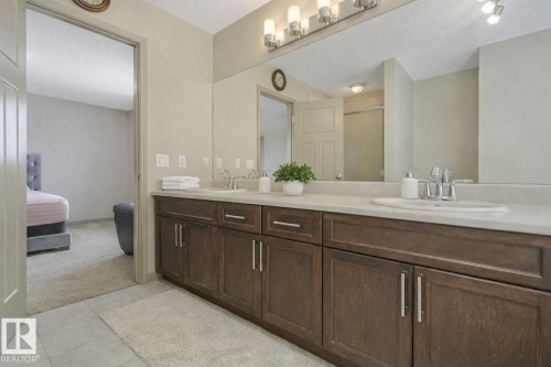Double vanity with wood-finish cabinetry, light-toned countertops, and dual undermount sinks - 21851 80 Avenue, Edmonton, AB - Indoor Photo Showing Bathroom