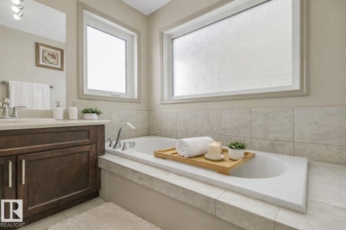 Deep soaking tub with chrome fixtures, surrounded by light-toned tile - 21851 80 Avenue, Edmonton, AB - Indoor Photo Showing Bathroom