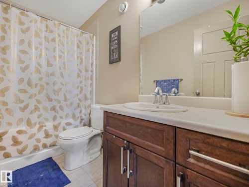 Full bathroom featuring a single vanity with a white countertop, undermount sink, and wood-finish cabinetry - 21851 80 Avenue, Edmonton, AB - Indoor Photo Showing Bathroom