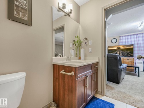 Bathroom vanity featuring a light-toned countertop, integrated sink, and wood-finish cabinetry with brushed nickel hardware - 21851 80 Avenue, Edmonton, AB - Indoor Photo Showing Bathroom