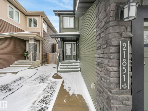 Modern facade featuring green horizontal siding and stacked stone accents - 21851 80 Avenue, Edmonton, AB - Outdoor