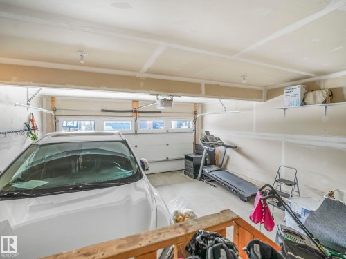 Two-car garage featuring a sectional overhead door with upper window inserts, concrete flooring, and overhead lighting - 21851 80 Avenue, Edmonton, AB - Indoor Photo Showing Garage