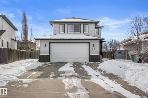 This property features a two-story exterior with light-colored siding, a dark brick accent, and a front-facing garage with a white door - 112 Lakeland Point(E), Beaumont, AB - Outdoor