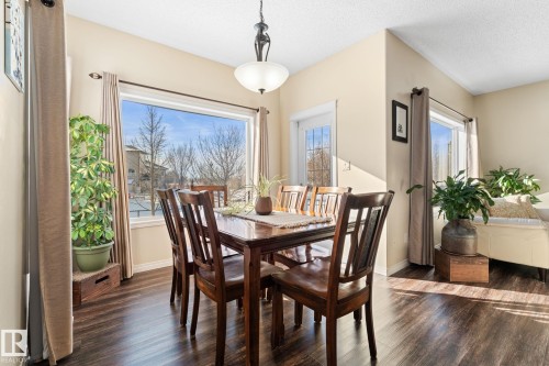 The property features a dining area with dark wood flooring and a large window, providing natural light - 112 Lakeland Point(E), Beaumont, AB - Indoor Photo Showing Dining Room