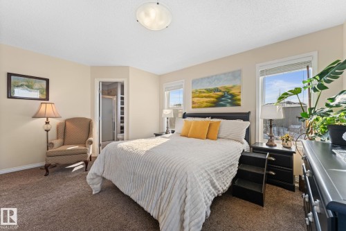 The property features a spacious room with carpeted flooring, two windows providing natural light, and a ceiling light fixture - 112 Lakeland Point(E), Beaumont, AB - Indoor Photo Showing Bedroom