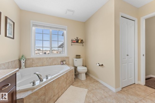The bathroom features a large soaking tub with tiled surround, a window providing natural light, and tiled flooring - 112 Lakeland Point(E), Beaumont, AB - Indoor Photo Showing Bathroom