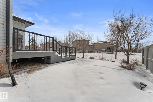 The property includes a spacious deck with dark railings, a fenced yard, and bare trees - 112 Lakeland Point(E), Beaumont, AB - Outdoor With Exterior