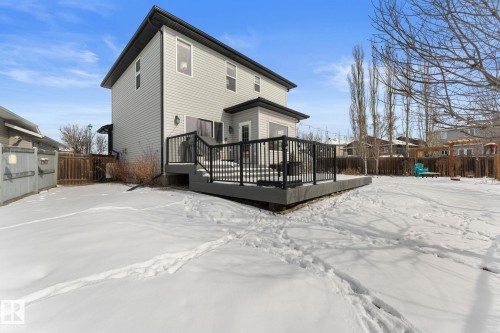 The property features a large deck with black railings overlooking a spacious, snow-covered yard - 112 Lakeland Point(E), Beaumont, AB - Outdoor With Exterior