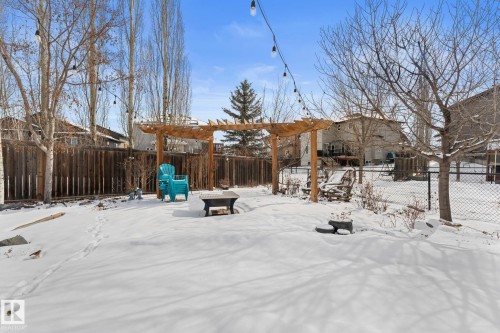 The property features a backyard with a wooden fence, a wooden pergola, and string lights - 112 Lakeland Point(E), Beaumont, AB - Outdoor
