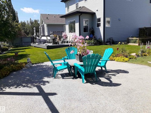 Expansive backyard featuring a well-maintained lawn, a spacious patio area, and a raised wooden deck perfect for outdoor enjoyment - 112 Lakeland Point(E), Beaumont, AB - Outdoor With Deck Patio Veranda