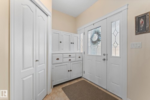 Entryway with a white front door featuring decorative glass inserts, a white storage cabinet with drawers and doors, and light-colored walls - 112 Lakeland Point(E), Beaumont, AB - Indoor Photo Showing Other Room