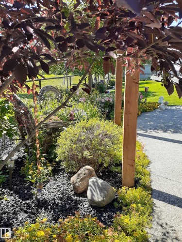 Landscaped garden bed featuring dark mulch, decorative rocks, and a variety of plantings - 112 Lakeland Point(E), Beaumont, AB - Outdoor
