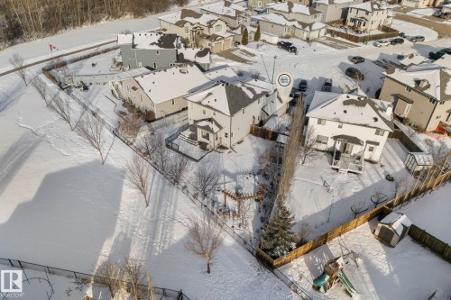 The property is set in a community with numerous detached homes, surrounded by snow-covered grounds and trees - 112 Lakeland Point(E), Beaumont, AB - Outdoor With View