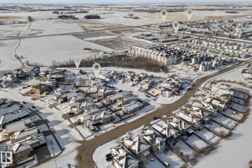 Aerial view of the community, showcasing residential properties with snow-covered roofs and surrounding open fields - 112 Lakeland Point(E), Beaumont, AB - Outdoor With View