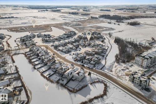 Aerial view showcasing a residential community with a variety of homes, a road, and a paved path - 112 Lakeland Point(E), Beaumont, AB - Outdoor With View