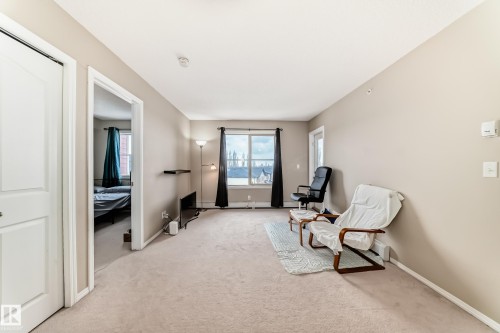 Carpeted living area with light beige wall paint - 404 12025 22 Avenue Sw, Edmonton, AB - Indoor Photo Showing Other Room
