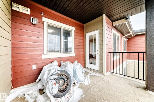 Exterior balcony featuring concrete flooring, black metal railing, and an exterior door with a window pane - 404 12025 22 Avenue Sw, Edmonton, AB - Outdoor With Exterior