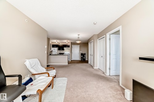 Open-concept living area featuring neutral carpeting and light-toned wall finishes - 404 12025 22 Avenue Sw, Edmonton, AB - Indoor