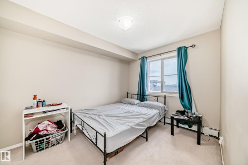 Carpeted bedroom with neutral wall tones, a double window, and a ceiling-mounted light fixture - 404 12025 22 Avenue Sw, Edmonton, AB - Indoor Photo Showing Bedroom