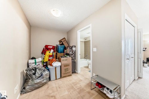 Hallway featuring tile flooring, neutral wall paint, and a textured ceiling - 404 12025 22 Avenue Sw, Edmonton, AB - Indoor Photo Showing Other Room