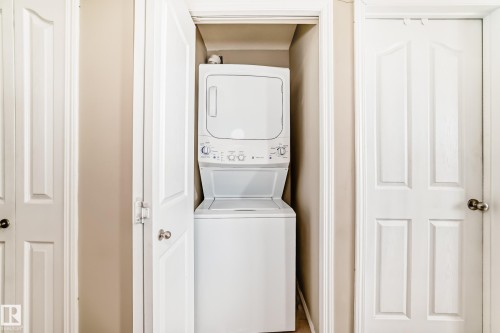 Dedicated laundry closet featuring a stacked white washer and dryer unit - 404 12025 22 Avenue Sw, Edmonton, AB - Indoor Photo Showing Laundry Room