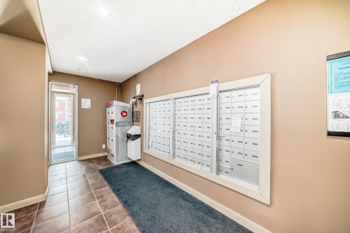Building entryway featuring a glass-paneled door, tiled flooring, and a bank of mailboxes - 404 12025 22 Avenue Sw, Edmonton, AB - Indoor Photo Showing Other Room