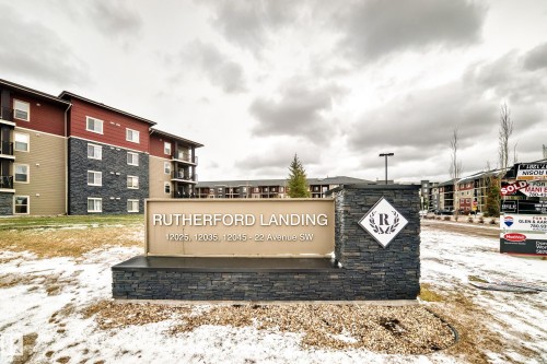 Main entry sign featuring stacked stone accents and a metallic finish panel with property identification - 404 12025 22 Avenue Sw, Edmonton, AB - Outdoor