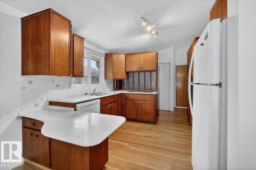 Kitchen featuring wood cabinetry, white countertops, and a white tiled backsplash - 6018 105A Street, Edmonton, AB 