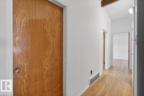 Hallway featuring wood-finish flooring, white walls, and wood-finish doors - 6018 105A Street, Edmonton, AB 