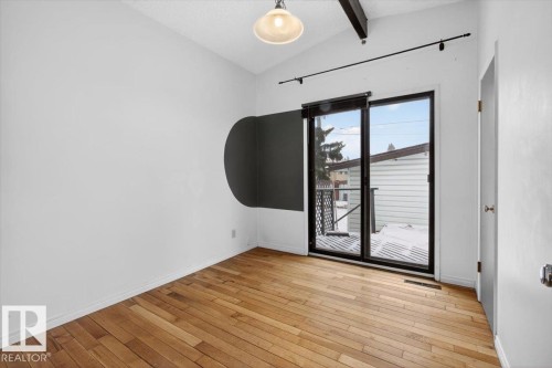 Room featuring wood flooring, a vaulted ceiling with exposed beam, and a ceiling-mounted light fixture - 6018 105A Street, Edmonton, AB 