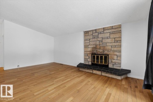 Stone-clad fireplace with a black tile hearth and a firebox featuring a golden grate - 6018 105A Street, Edmonton, AB 
