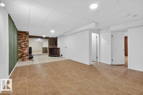 Spacious lower-level area featuring ceramic tile flooring and a drop ceiling with recessed lighting - 6018 105A Street, Edmonton, AB 
