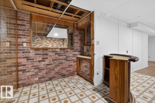 Recreational space featuring brick-style wall paneling, a built-in wet bar, and a patterned tile floor - 6018 105A Street, Edmonton, AB 