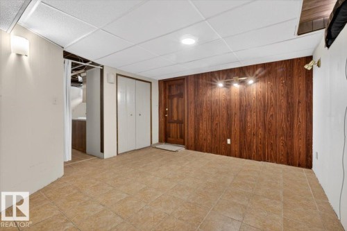 Finished interior space featuring tile flooring and a wood-paneled accent wall - 6018 105A Street, Edmonton, AB 