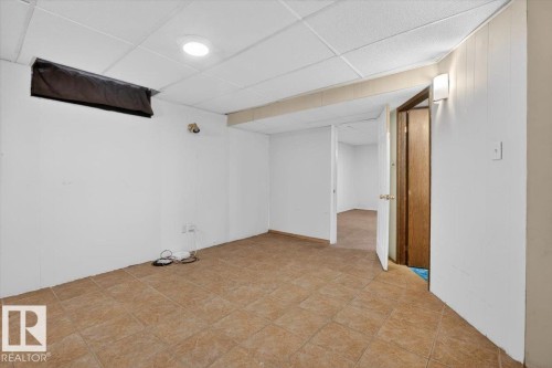 Spacious room featuring neutral-toned tile flooring, white walls, and a white drop ceiling with recessed lighting - 6018 105A Street, Edmonton, AB 