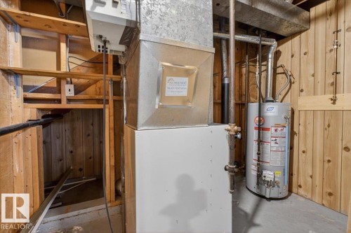 Utility area featuring a water heater, furnace system, and wood-paneled walls - 6018 105A Street, Edmonton, AB 