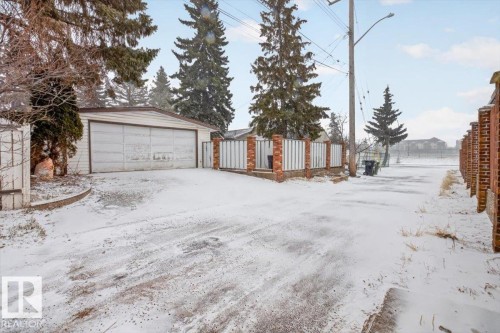 Detached garage with a paneled door, accompanied by a brick and vertical slat fence - 6018 105A Street, Edmonton, AB 