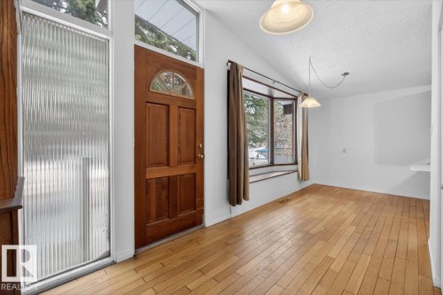 Entryway featuring a wood-paneled door with arched glass detail, alongside a full-height reeded glass sidelight and transom windows - 6018 105A Street, Edmonton, AB 