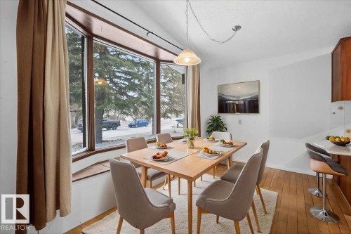 Dining area featuring wood-finish flooring and a large bay window - 6018 105A Street, Edmonton, AB 