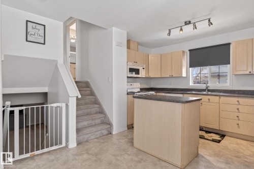 Kitchen featuring light wood-finish cabinetry, dark countertops, and a central island - 1904 36 Avenue, Edmonton, AB - Indoor Photo Showing Kitchen
