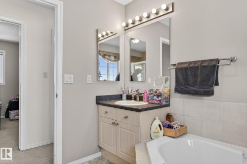 Bathroom vanity featuring a built-in sink, dark countertop, and light-toned cabinetry with brushed nickel hardware - 1904 36 Avenue, Edmonton, AB - Indoor Photo Showing Bathroom