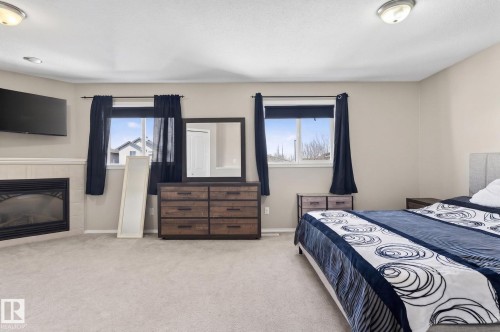 Carpeted room featuring a fireplace with a white tile surround, two windows, and a ceiling-mounted light fixture - 1904 36 Avenue, Edmonton, AB - Indoor Photo Showing Bedroom