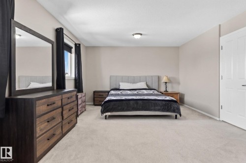 Expansive carpeted room featuring a window with dark drapes, light-colored walls, and a ceiling-mounted light fixture - 1904 36 Avenue, Edmonton, AB - Indoor Photo Showing Bedroom