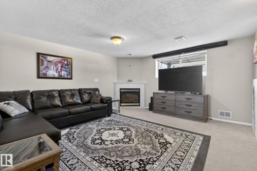Living area featuring a corner fireplace with a white mantel, light beige walls, recessed window, and neutral carpet flooring - 1904 36 Avenue, Edmonton, AB - Indoor Photo Showing Living Room With Fireplace