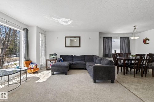Open-concept living area featuring a large picture window, carpeted flooring, and a distinct dining space with hard-surface flooring - 1904 36 Avenue, Edmonton, AB - Indoor Photo Showing Living Room