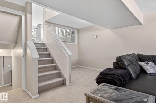 Carpeted staircase with painted white railings ascending to an upper level, complemented by a window with white louvered blinds - 1904 36 Avenue, Edmonton, AB - Indoor Photo Showing Other Room