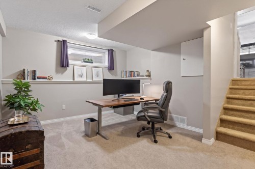 Carpeted room featuring a window with decorative valances, built-in shelving, a recessed ceiling light, and a carpeted staircase - 1904 36 Avenue, Edmonton, AB - Indoor Photo Showing Office